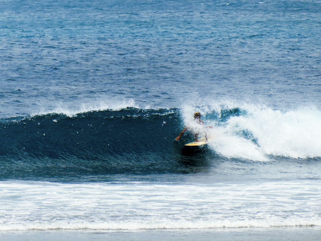 Surfer riding a reef point on the West Sumbawa coast
